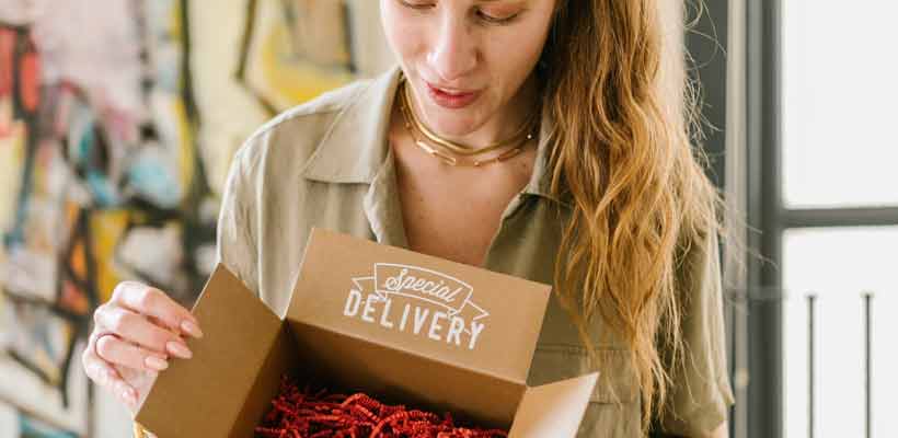 A young woman opening an eCommerce delivery box