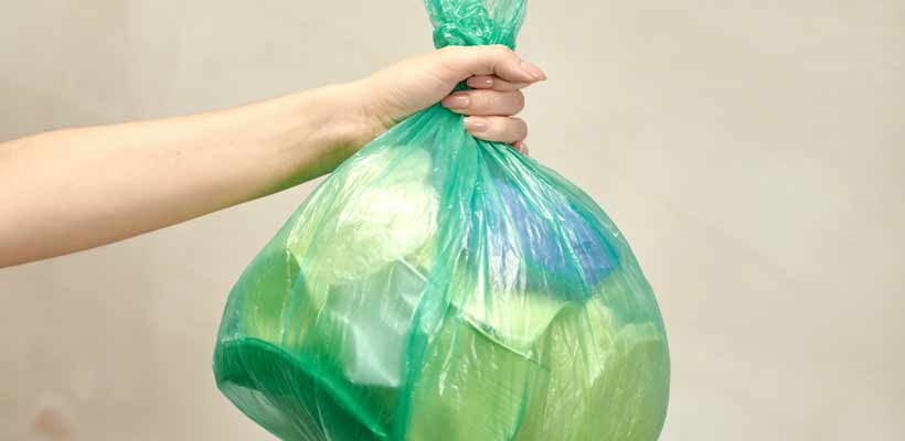 A person holding a plastic bag full of waste packaging
