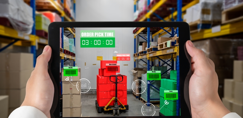 A person holding a tablet scanning a warehouse with packing barcodes to identify order pick times