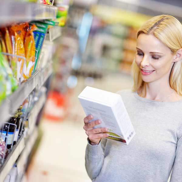 A woman looking at retail packaging in a supermarket