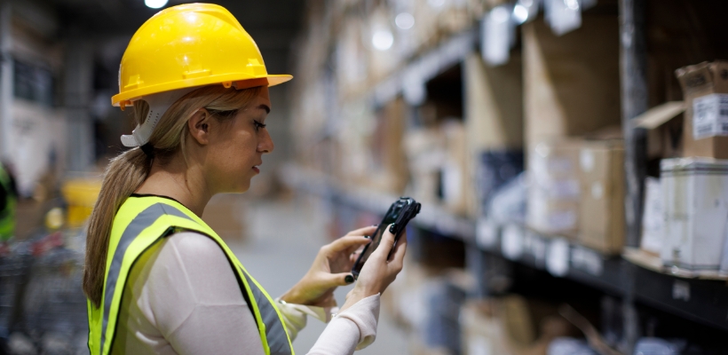 Someone in a warehouse using a RFID reader to scan parcels.