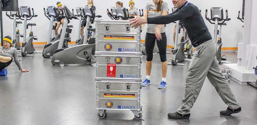 Football skip A kit manager pushing a stack of aluminium kit skips through a gym.