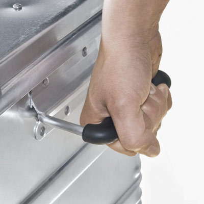 Kit skip handle A person lifting an aluminium kit skip by its handle.