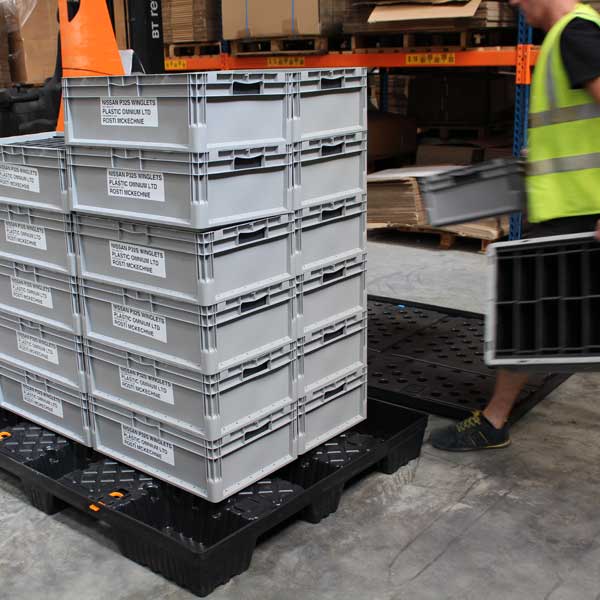 Reusable packaging A person stacking reusable packaging on a pallet.