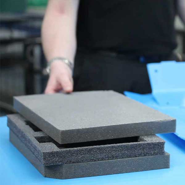 Foam packaging A person picking up a pile of foam packaging inserts.