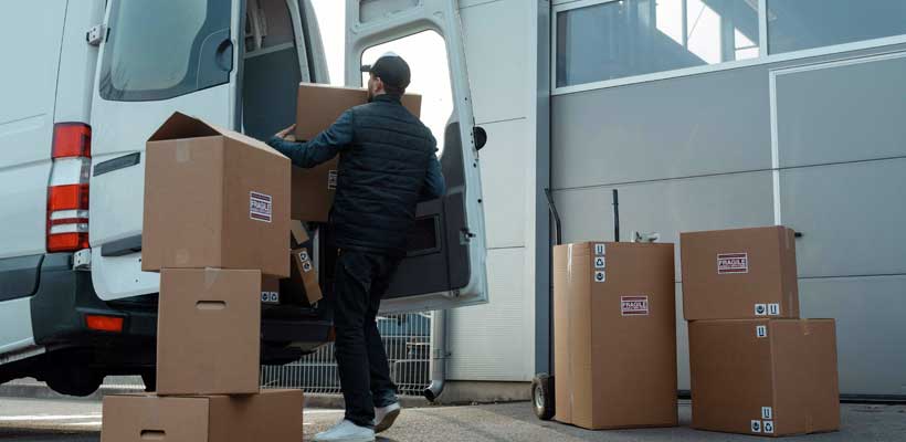 Packaging size A person loading cardboard boxes into a van.