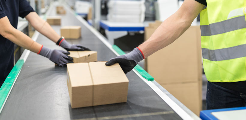 Packing PPE A person picking up a box from a conveyor belt.