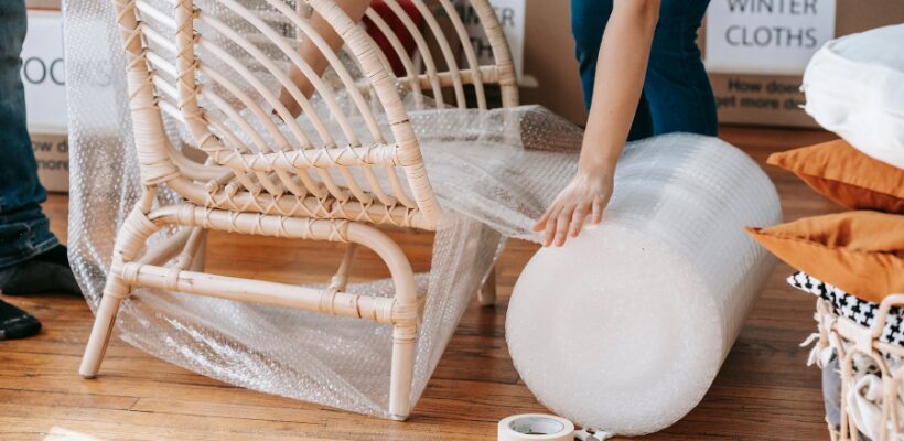 a person wrapping a large item with a roll of bubble wrap
