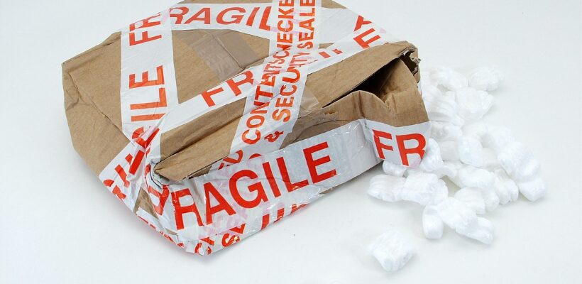 packaging mistakes img 1 a damaged cardboard box with fragile tape around it and packing peanuts spilling out