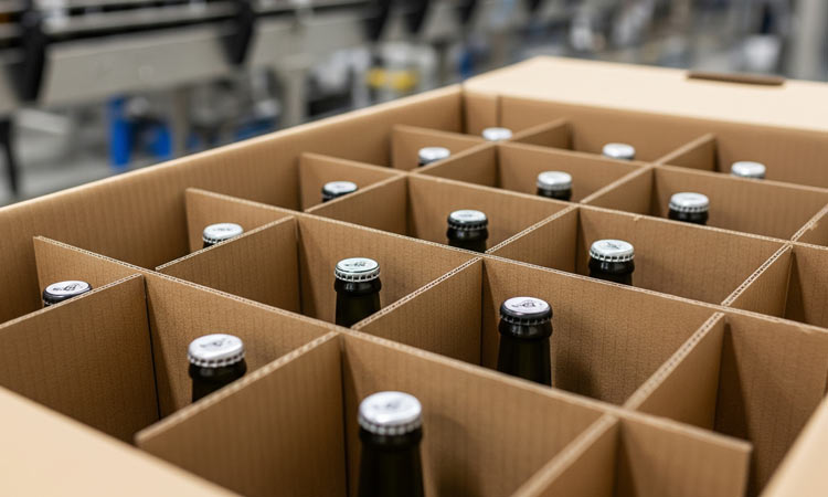 Beer bottles in a cardboard box with dividers at a bottling plant.