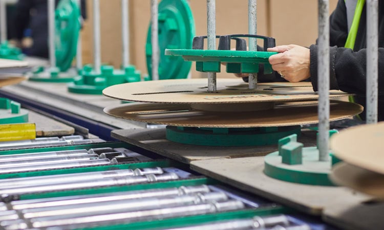 Cardboard spool manufacturer A person assembling a cardboard spool on an assembly line