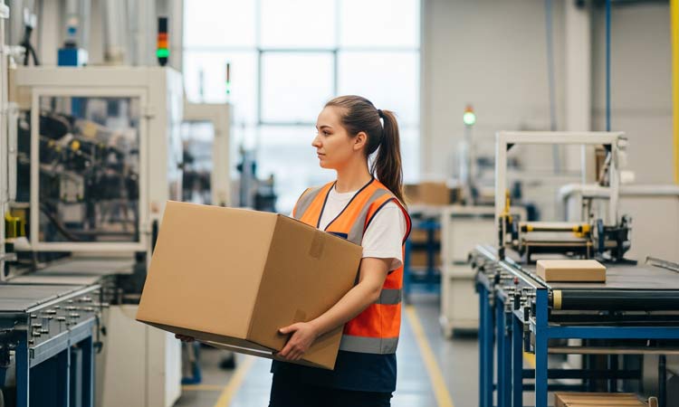 A person carrying a single wall packaging box in a factory