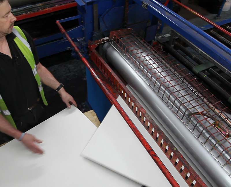 Coated cardboard A person coating cardboard in a factory