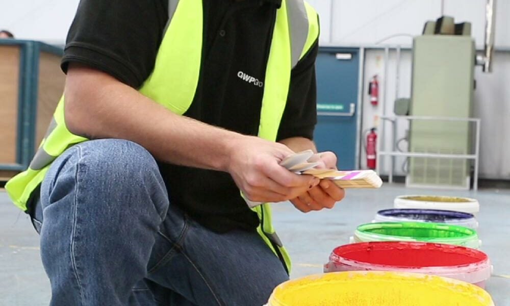A person checking the colours of cardboard coatings in a factory