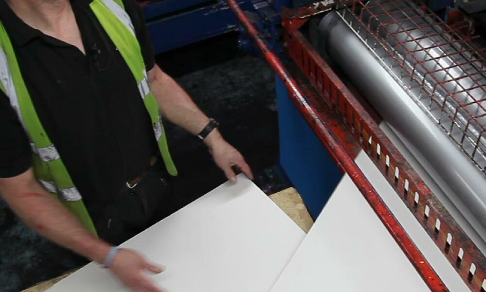 A person handling coated cardboard in a factory