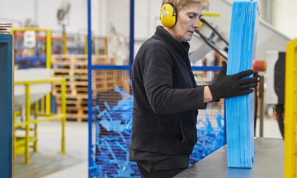 A person loading plastic sheet materials into packaging manufacturing equipment