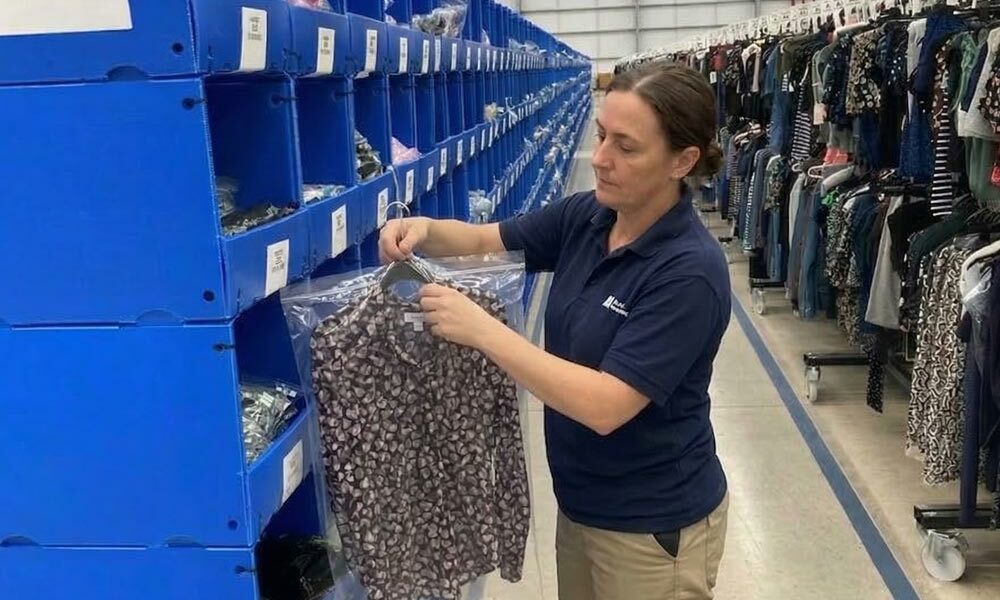 A person taking an item of clothing out of a free standing correx stacking pick bin in a fulfilment centre